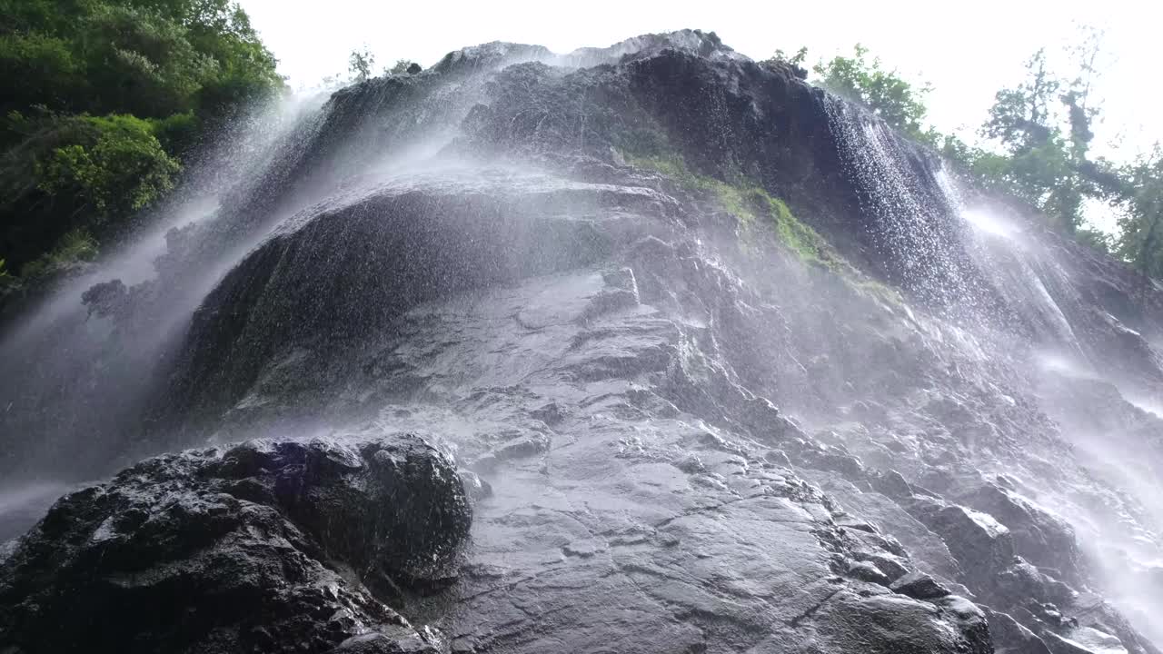 瀑布从山岩顶部流下，营造出梦幻般的柔和细雨效果视频下载