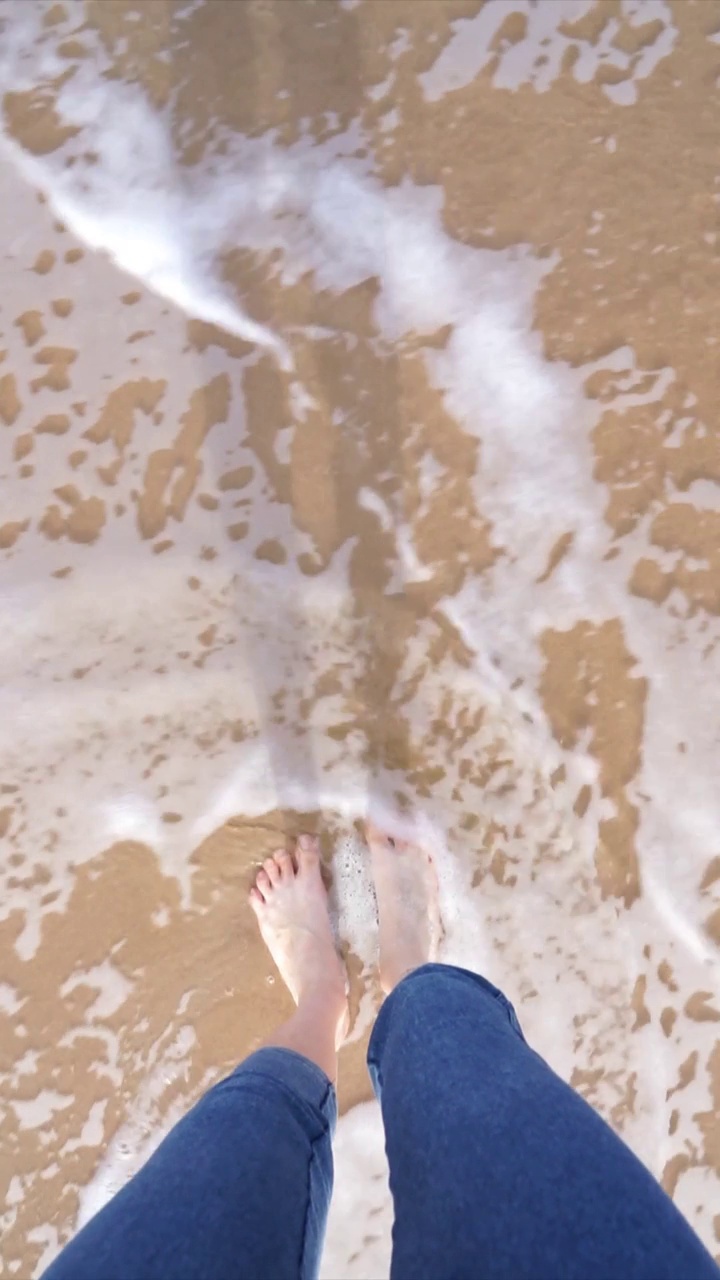 海滩上女人的脚被海浪打湿了视频素材