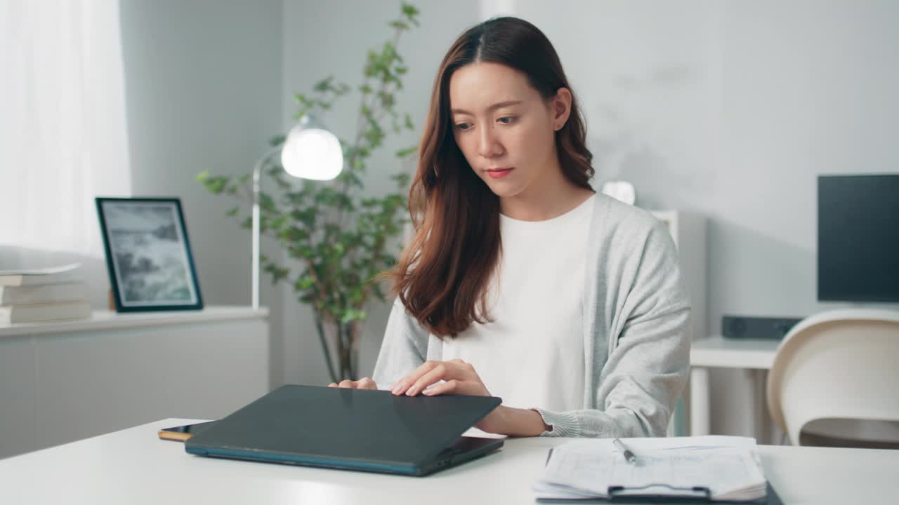 积极的年轻亚洲女性雇员或自由职业者使用电脑笔记本电脑，在键盘上打字和在家远程工作，年轻的员工多任务处理花时间在家里的办公室工作视频下载