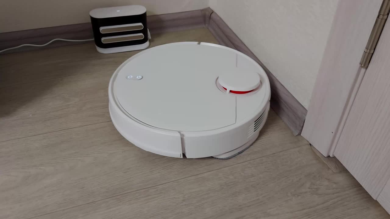 一个现代的白色机器人吸尘器在家里清理地板上的灰尘。电子助理打扫房间，做家务视频素材