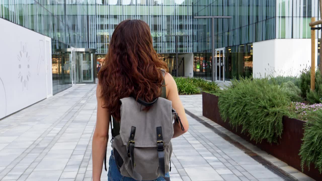 十几岁的女学生背靠背背着双肩包走过校园。回到学校，高中，大学视频下载