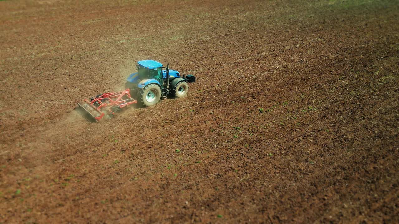 农用拖拉机在播种前犁地。农用机械用耙子在耕地上犁地。视频素材