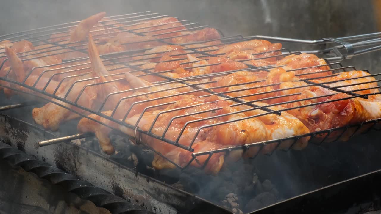 美味的鸡肉在户外烧烤架上煎炸。调味料落在新鲜的烤鸡翅上。夏日派对美食点子。多汁的烤鸡腿视频素材