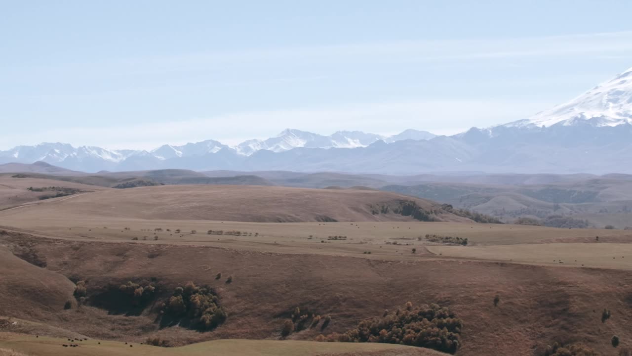 风景如画的山谷，黄色的草甸和巨大的寒冷的山峰，白色的山峰。有创造力。清晨的薄雾中，白雪覆盖着小山视频素材