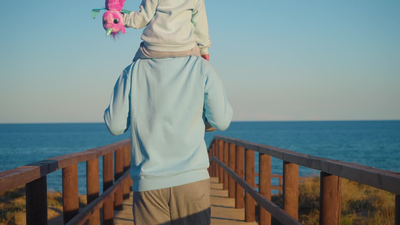 幸福的家庭。女儿小女孩坐在父亲男人的脖子上，描绘了一架飞机的飞行。父女生活方式视频素材