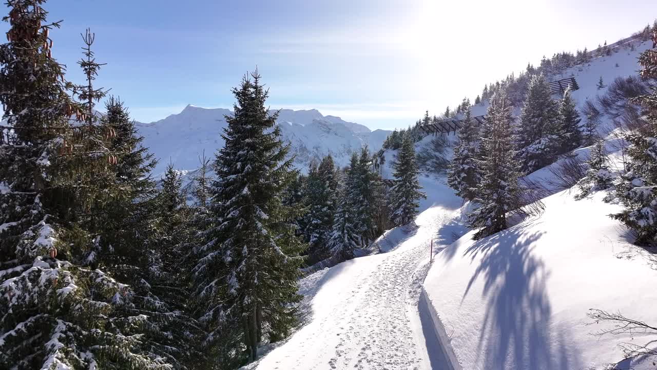 在阿德尔博登一个阳光明媚的冬日，雪山小径上的脚印。无人机拍摄视频素材