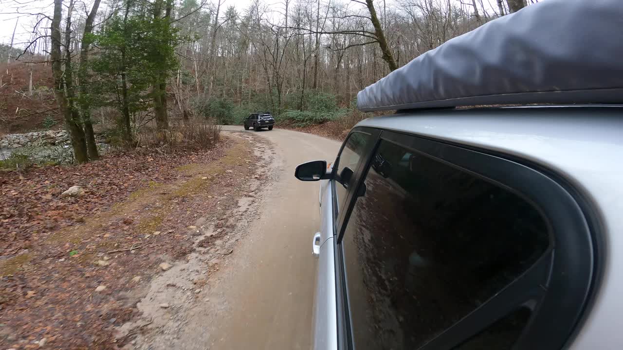 两辆陆路车辆行驶在风景秀丽的山溪周围的弯道上视频素材