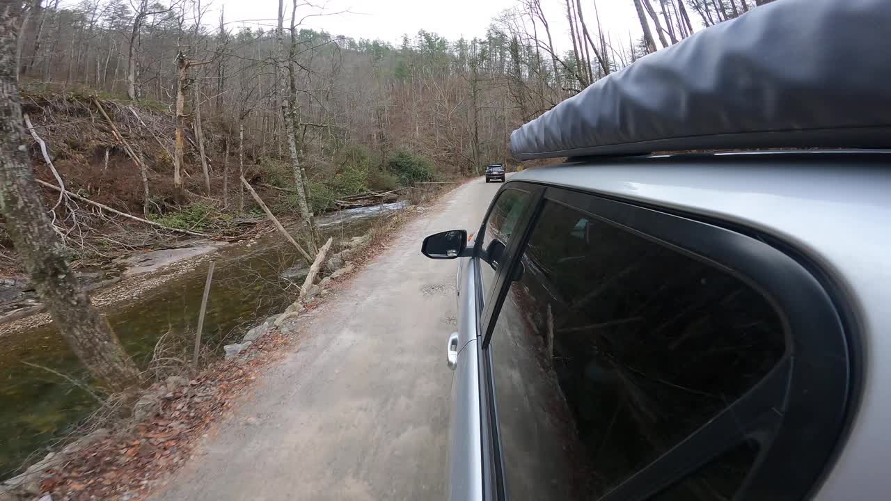 两辆陆路车辆沿着风景秀丽的山路，沿着小溪和过桥行驶视频素材