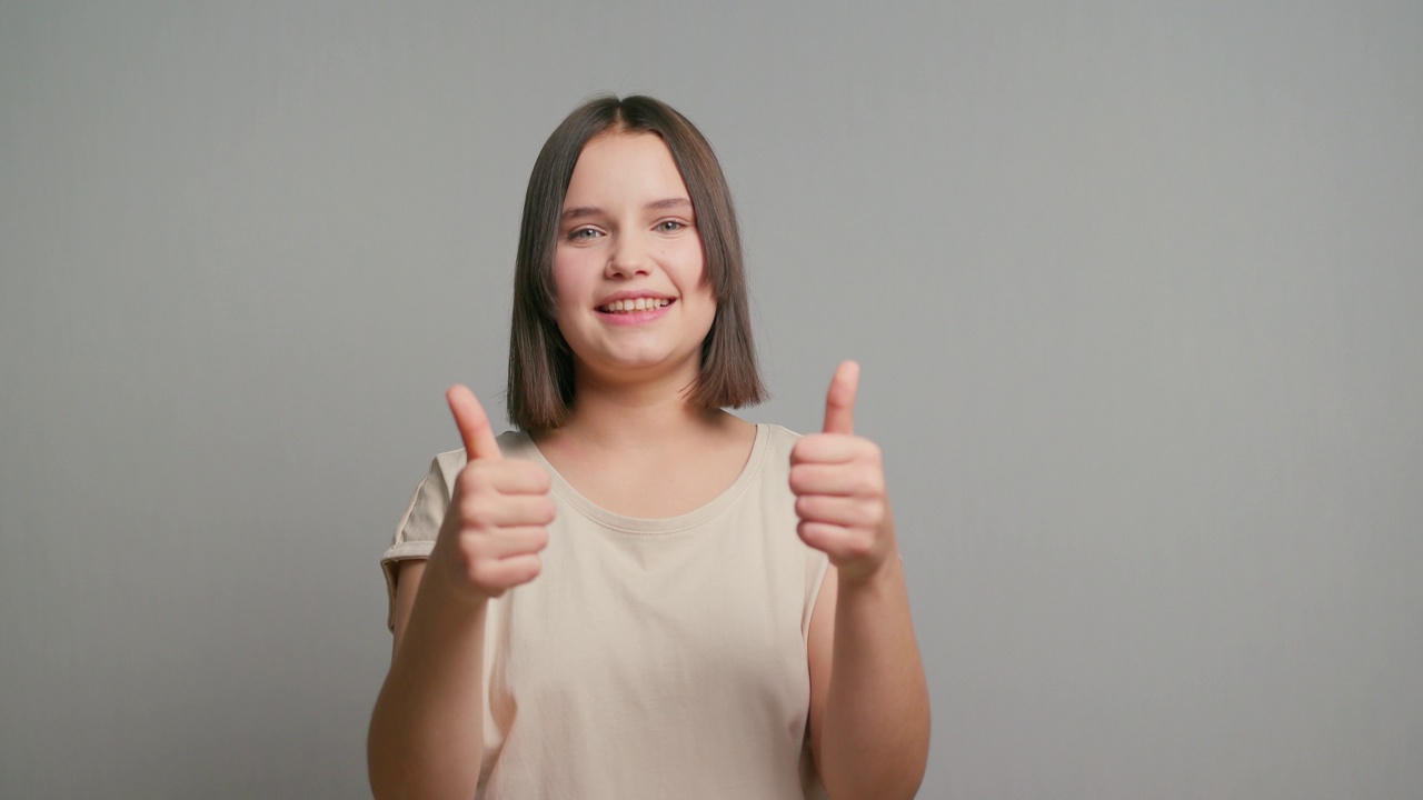 一个自信的拉丁少女站在灰色的背景上，竖起大拇指表示赞同，像史密斯一样推荐视频素材