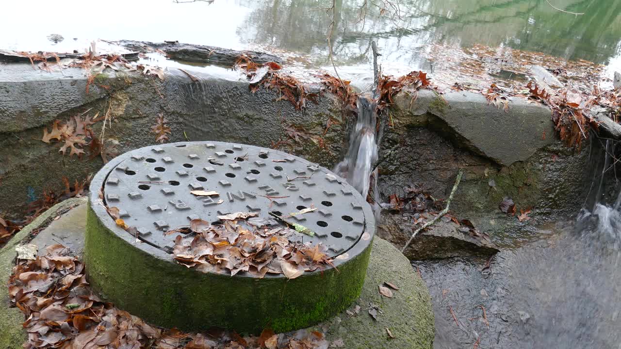 带有秋叶和排水管的高架下水道通道上的人孔盖视频素材