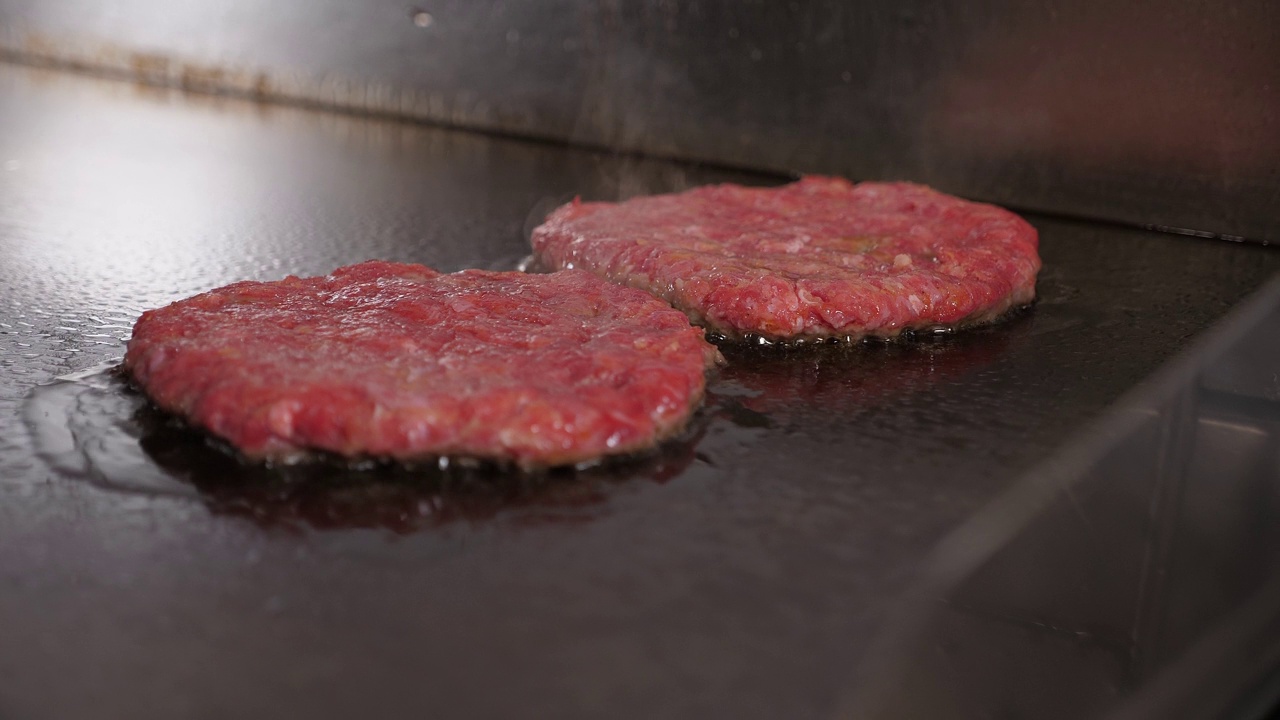 餐厅厨房里煎的两个肉汉堡的特写。视频素材