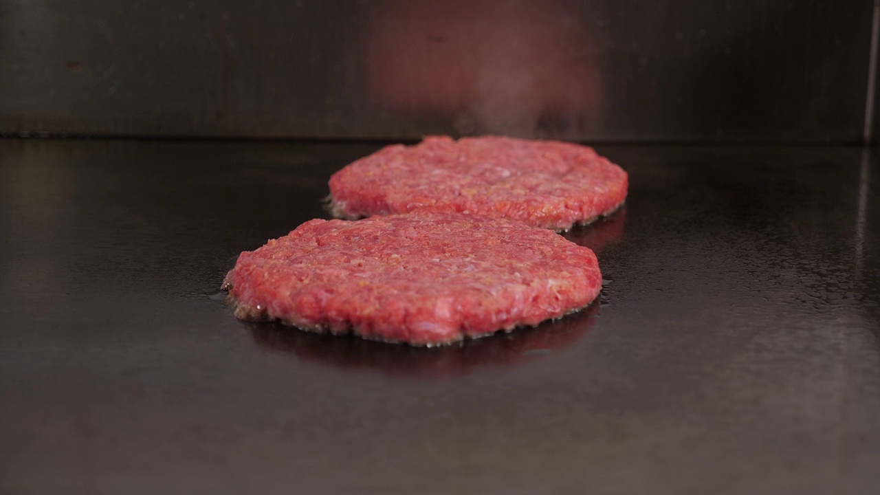 餐厅厨房里煎的两个肉汉堡的特写。视频素材