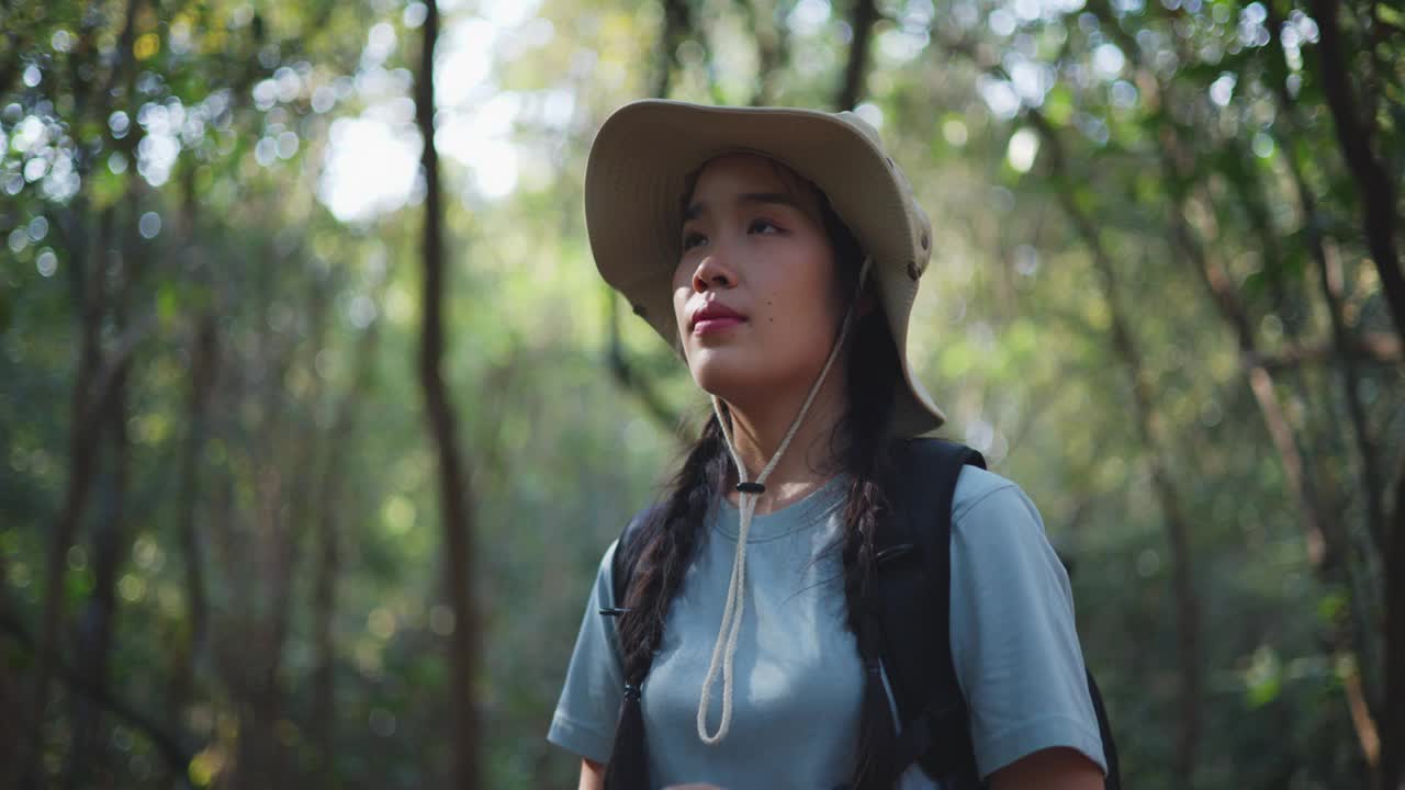 年轻的亚洲女背包客在秋天的森林里使用数码相机视频素材