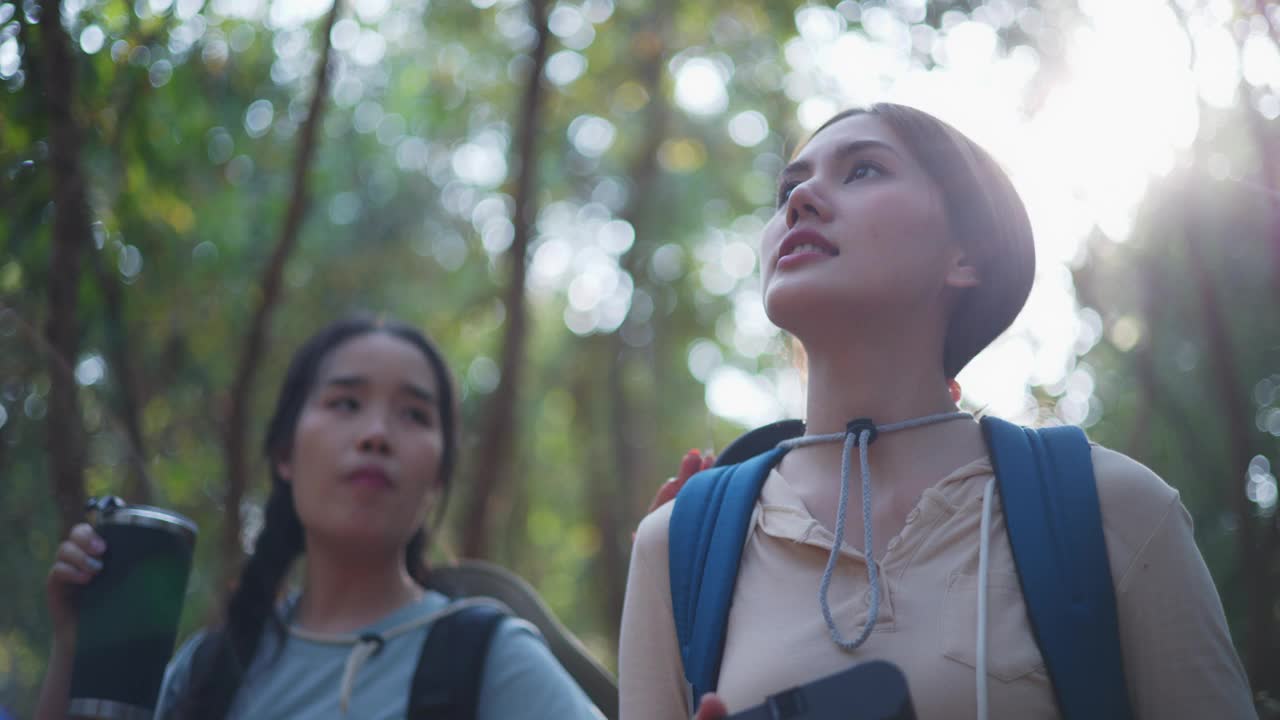 两个年轻的亚洲背包女在森林里带着数码相机走在小路上视频素材