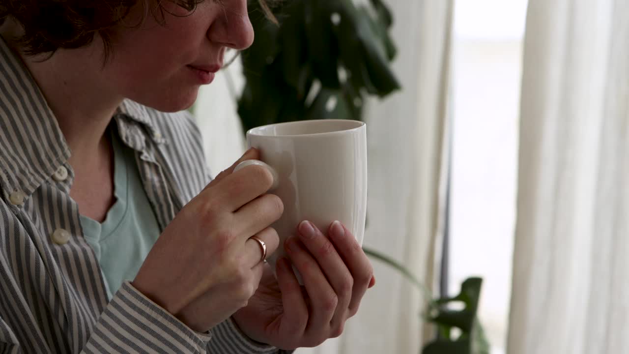 冬天里，一个女人从杯子里啜了一口茶视频素材