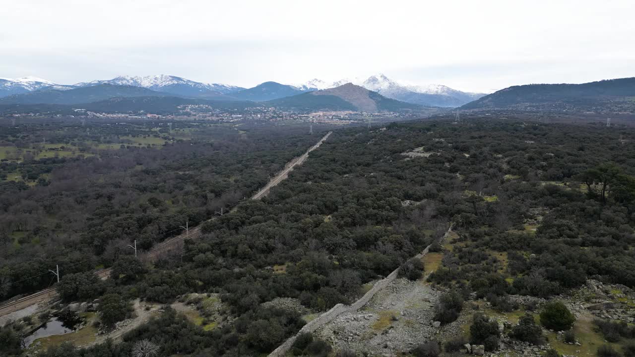 西班牙马德里瓜达拉玛山脉的鸟瞰图，被雪覆盖的山脉和火车轨道。无人机、山脉、云景、森林、植被、树木和自然的概念。视频下载