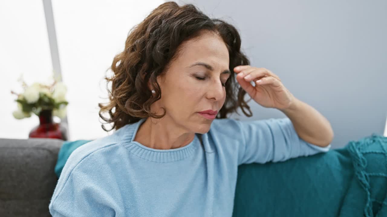 成熟的卷发女人在舒适的客厅里看起来很紧张。视频素材