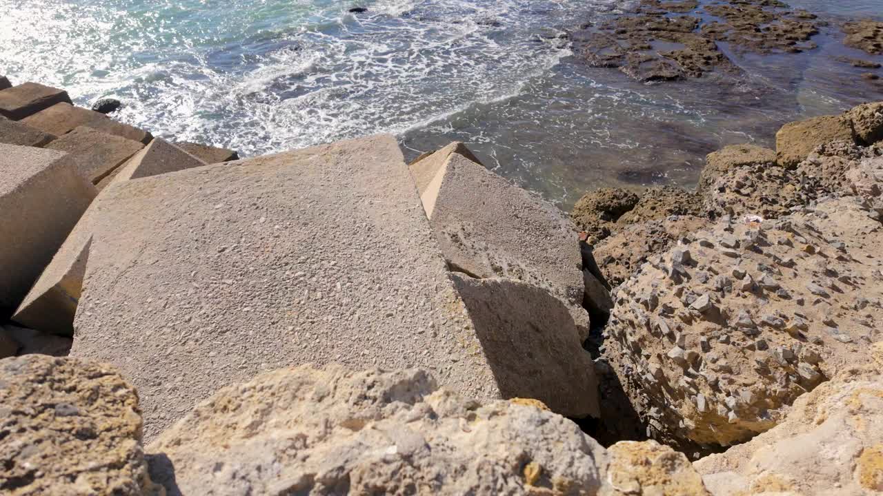 混凝土防波堤在晴朗的天空下通向波光粼粼的大海视频素材