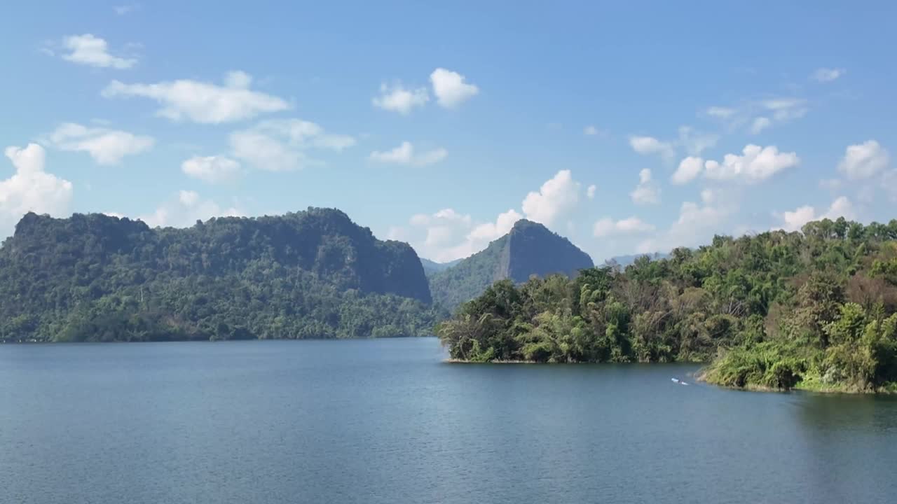 泰国清莱省，从Mae Suai大坝观景台的高处俯瞰山景，水面上的船只被洪水淹没，湛蓝的天空映衬着全景的山脉。视频下载