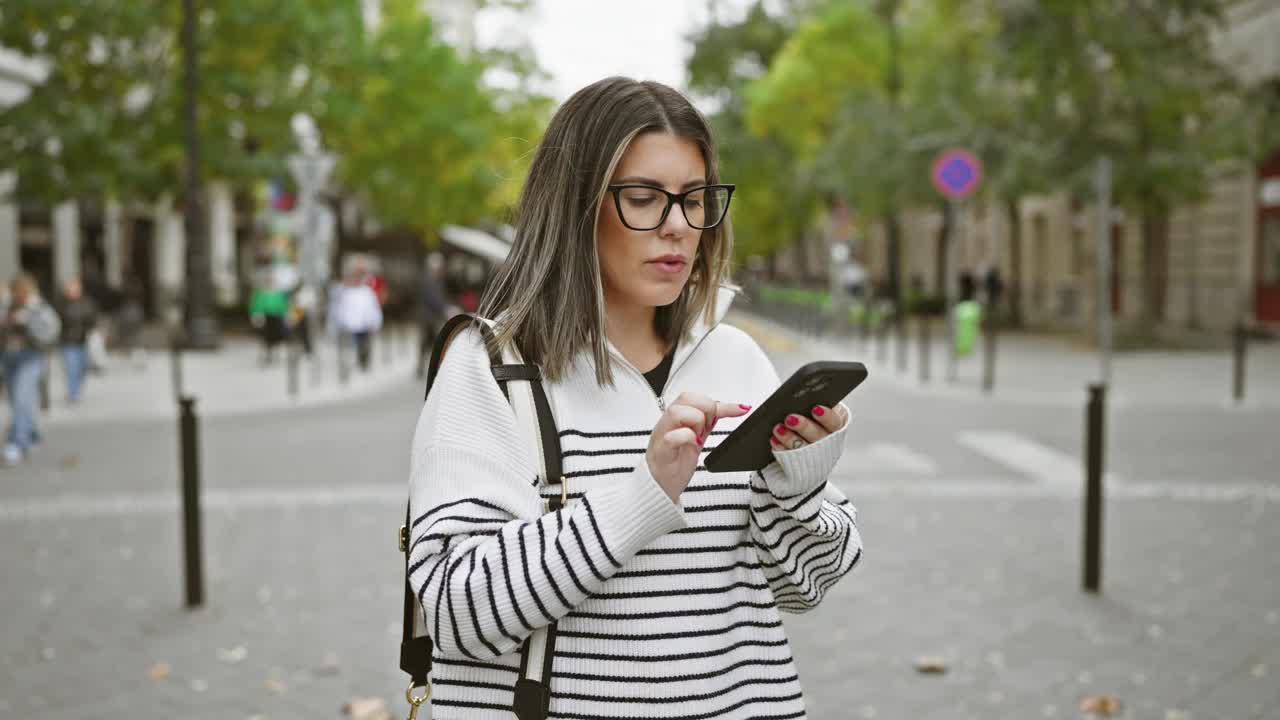 一位戴眼镜的女士在布达佩斯熙熙攘攘的街道上使用智能手机。视频素材