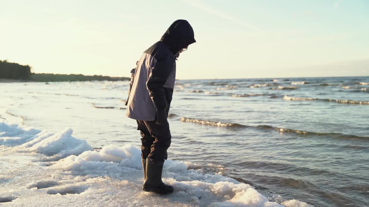 孩子在海湾水域的冬季海滩上玩浮冰和雪视频素材