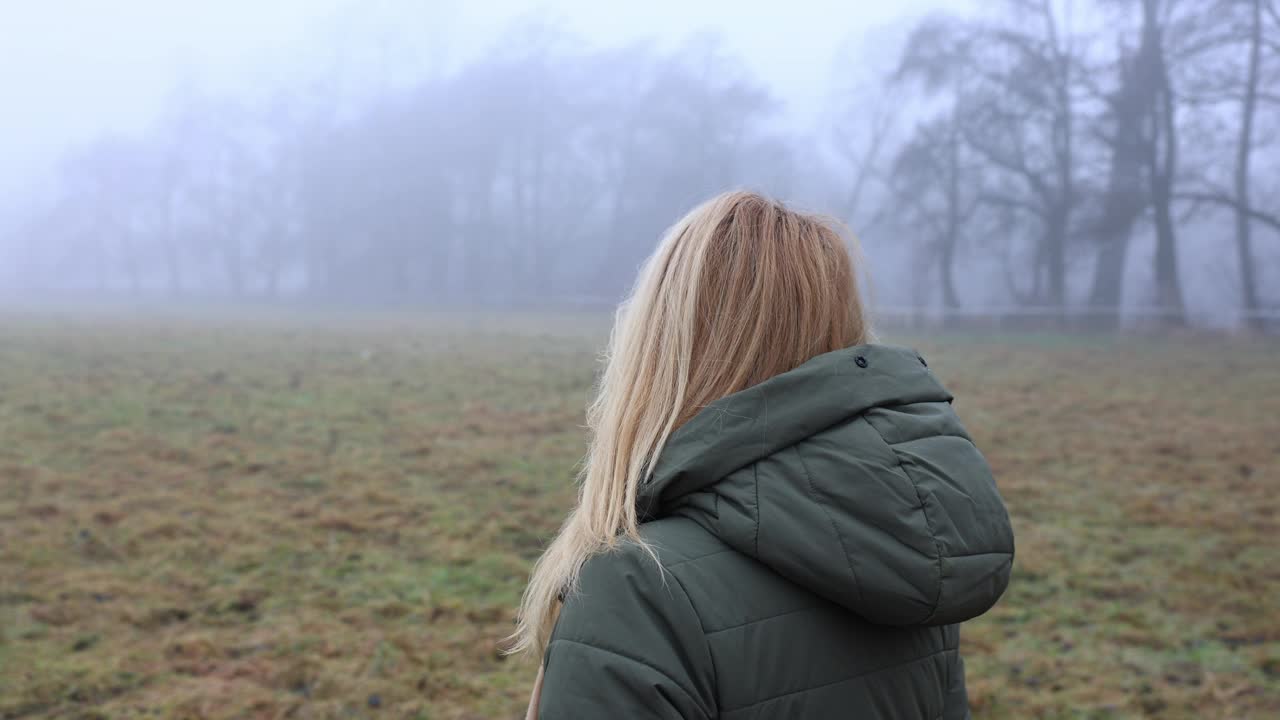 穿着连帽大衣的沉思女人独自站在雾中视频下载