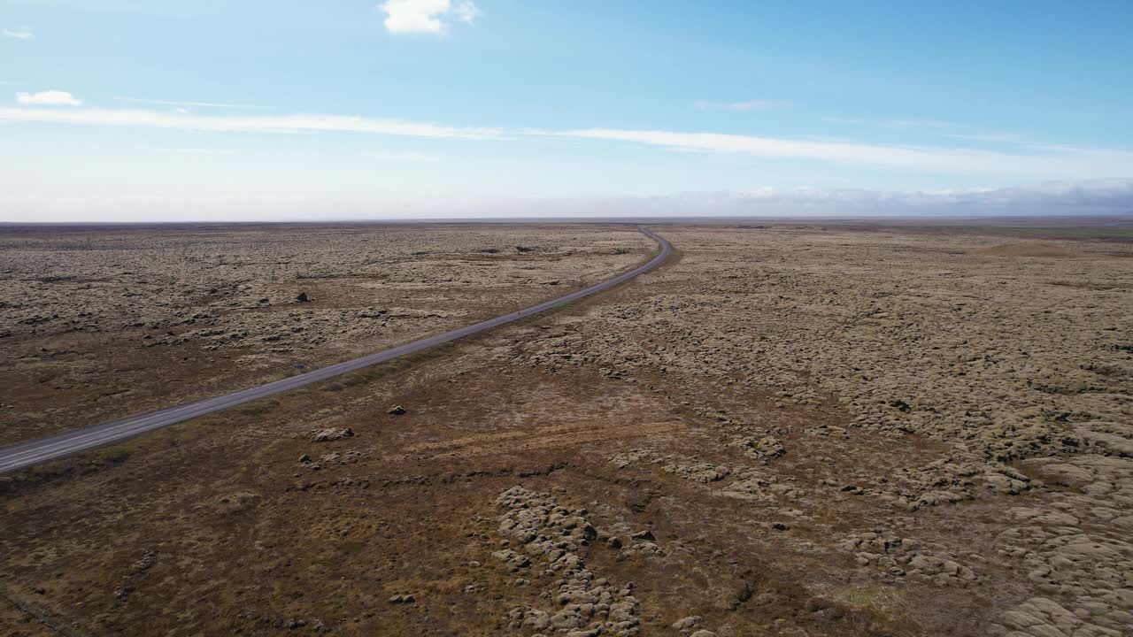 鸟瞰图:冰岛晴朗的天空下，一条荒芜的道路穿过一片贫瘠的土地视频素材