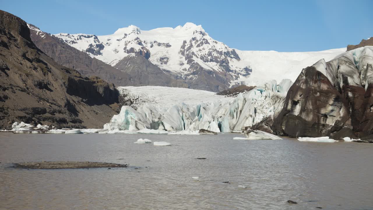 冰岛蔚蓝的天空下，冰川泻湖上漂浮着浮冰和白雪皑皑的山脉视频素材