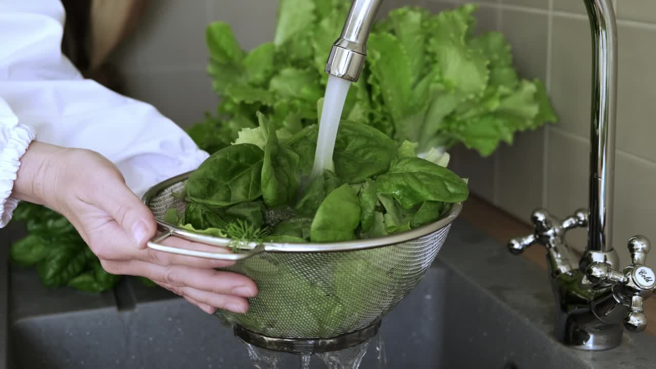 在厨房用流水洗菠菜叶。健康饮食视频素材