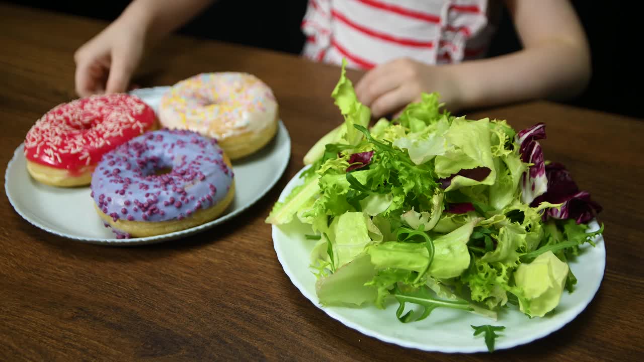 孩子选择了健康的食物，一盘沙拉而不是甜甜圈。视频下载