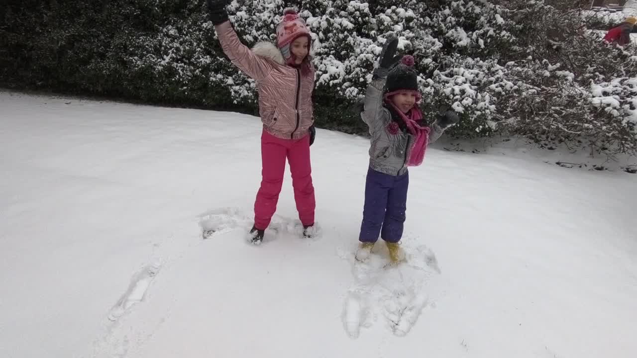 两姐妹在暴风雪中快乐地跳舞。视频下载