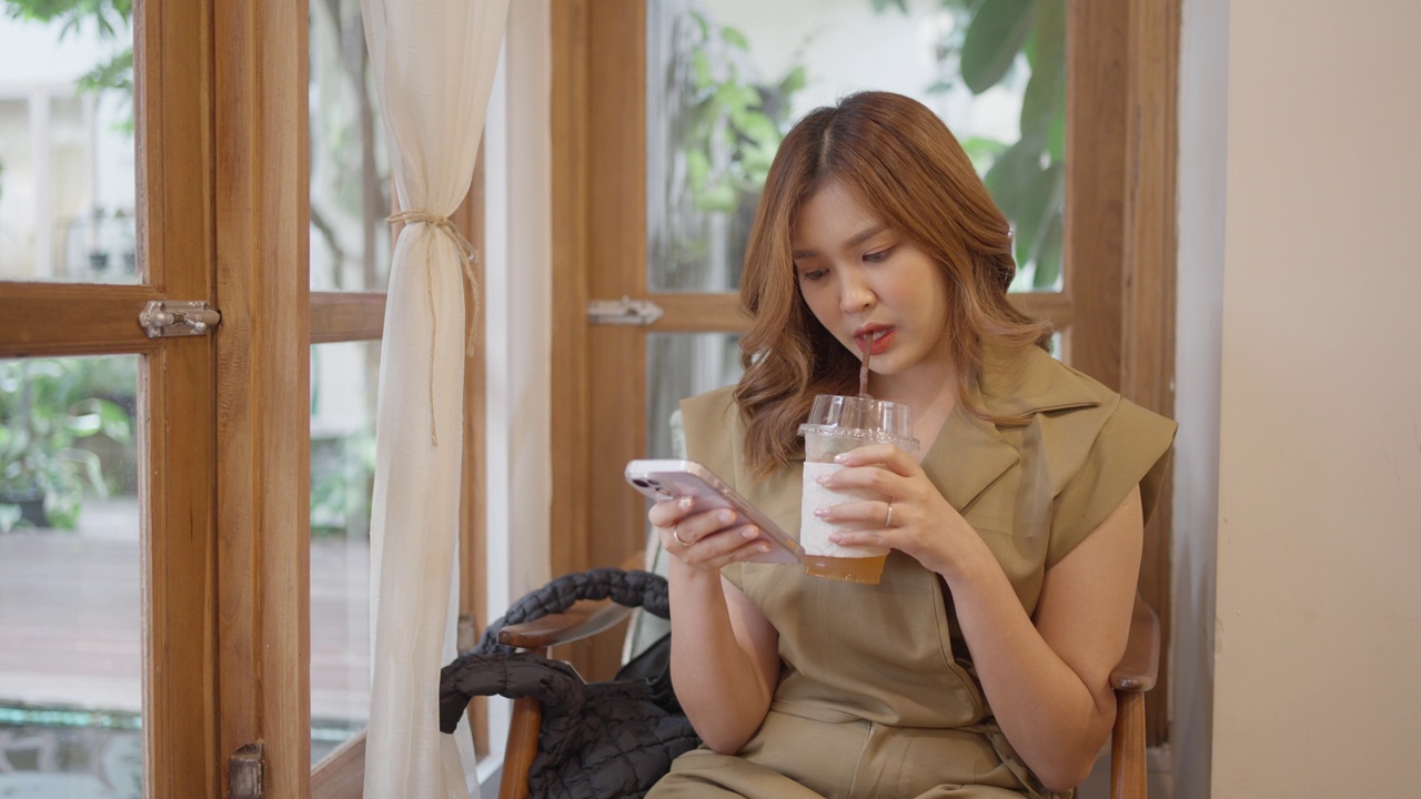 一个亚洲女人在咖啡馆里通过电话轻松地上网。视频素材