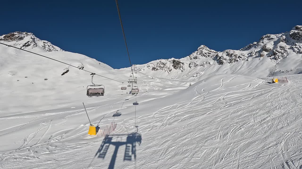 在一个美好的阳光明媚的日子里，滑雪者的缆车正在移动到滑雪道的顶部。最佳滑雪胜地视频下载