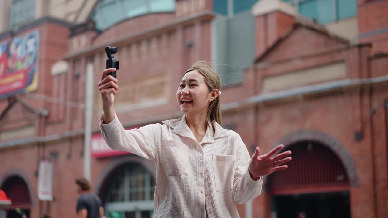 年轻的日本女子拿着相机说话，就像网红在城市旅行视频一样视频素材