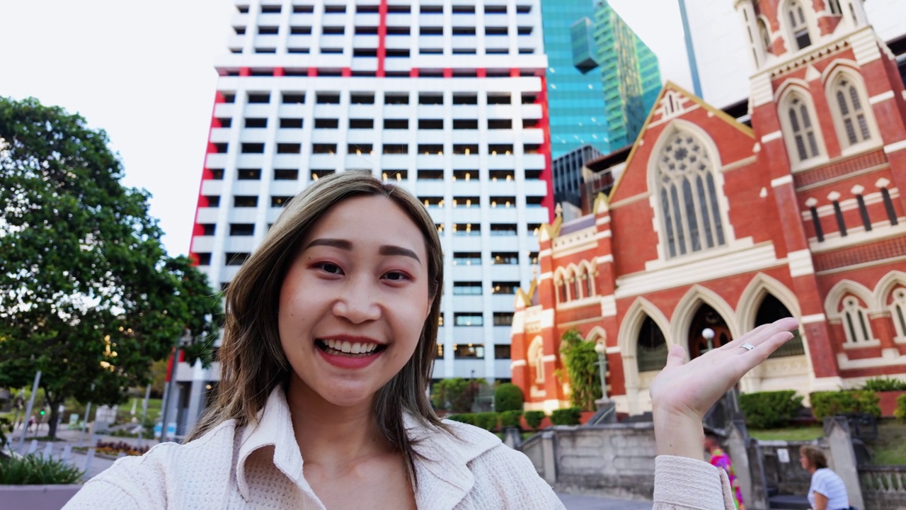 年轻的日本女子拿着相机说话，就像网红在城市旅行视频一样视频素材