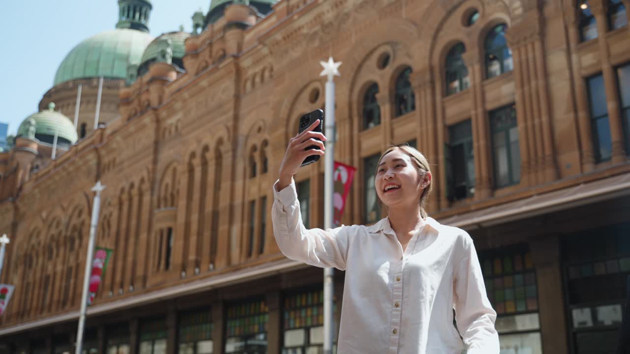 年轻的日本女子拿着相机说话，就像网红在城市旅行视频一样视频素材