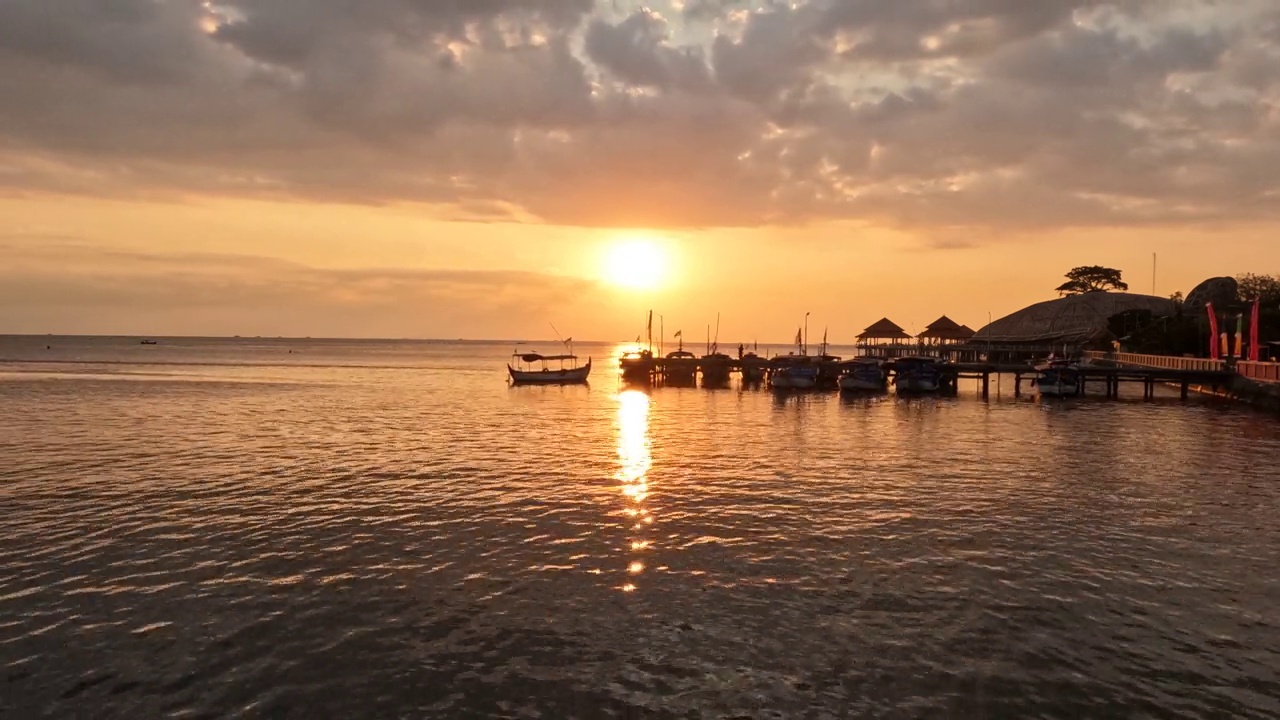 美丽的夕阳在海面上美丽的波浪。令人惊叹的日落或日出天空在海滩与渔民的船码头。视频素材