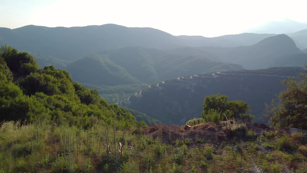 远处的鸟瞰图捕捉到了通往希腊北部维科斯峡谷的蜿蜒狭窄的道路，这条道路充满了曲折和急转弯，蜿蜒在扎戈里地区的山上。视频素材