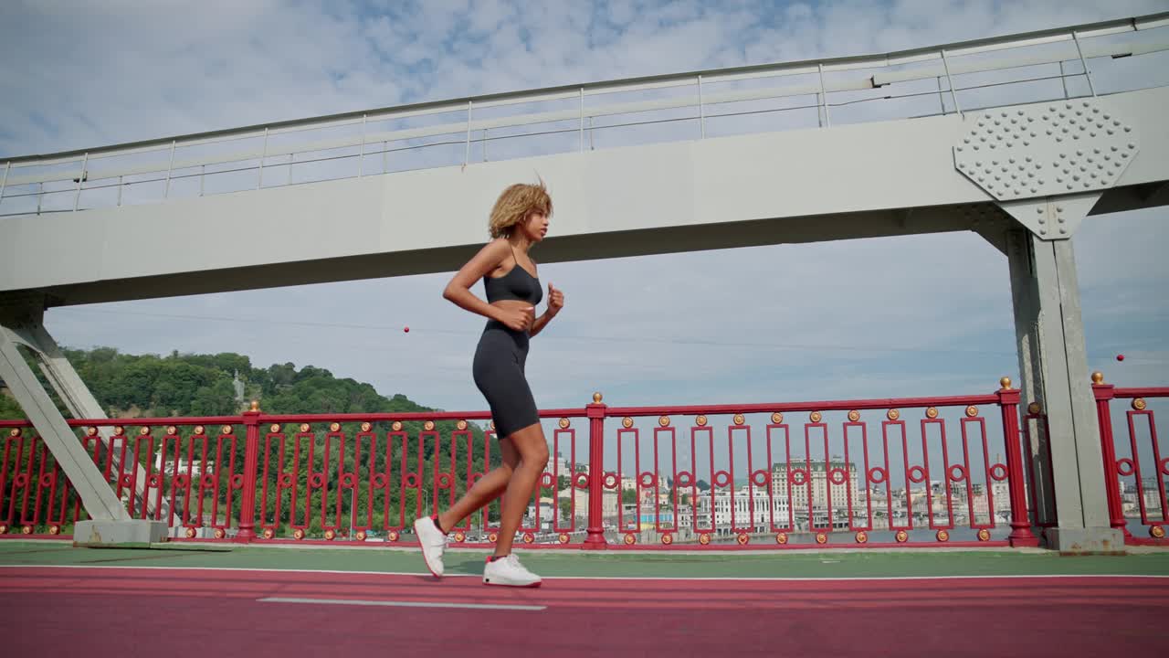 年轻的非裔美国女子跑步者在城市桥户外慢跑视频素材