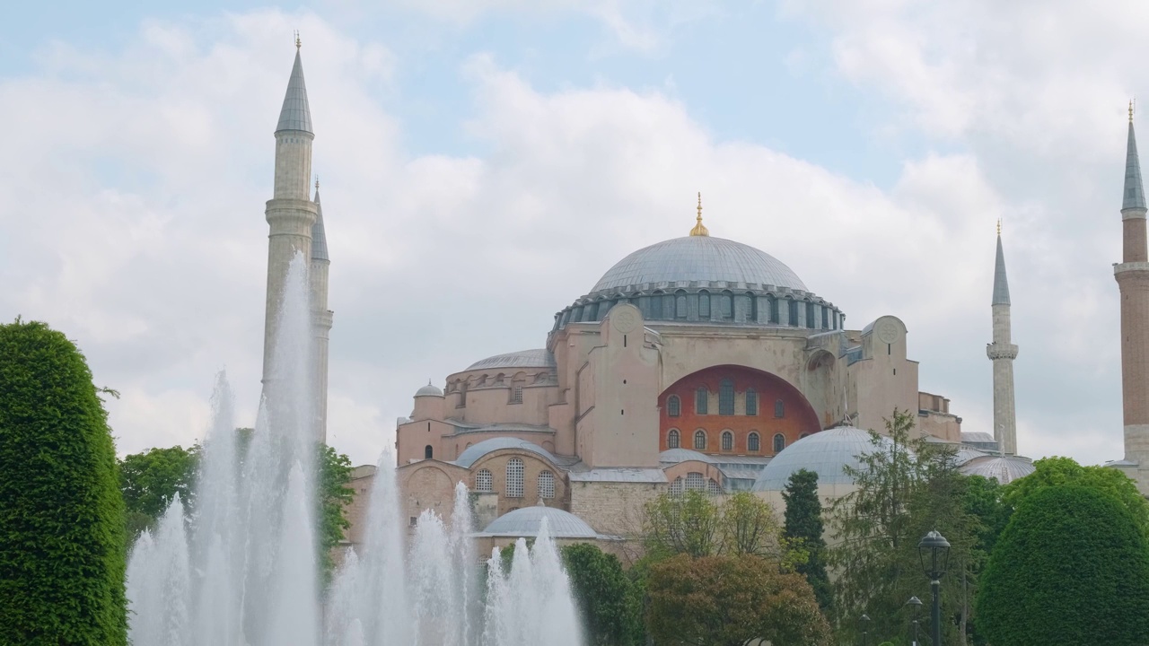 在土耳其伊斯坦布尔的绿色花园中，Sultanahmet公园的喷泉、圣索菲亚大教堂和奥斯曼清真寺视频素材