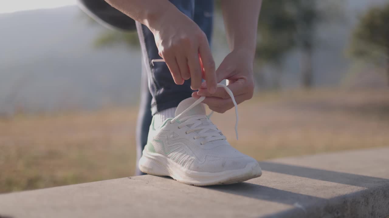 在户外健身概念中，年轻的健身女性系鞋带视频素材