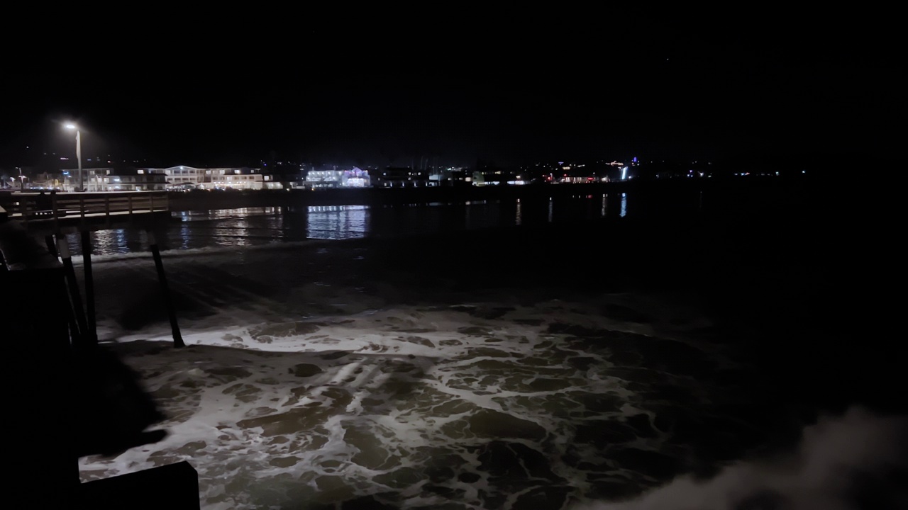 在夜间的暴风雨中，巨大的海浪冲击着海滩的海堤视频素材