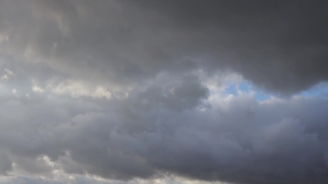 这是一个阴沉的日子，灰色的雨云飘过黑暗的天空，预示着要下雨。阴雨天气里神奇的天空视频下载