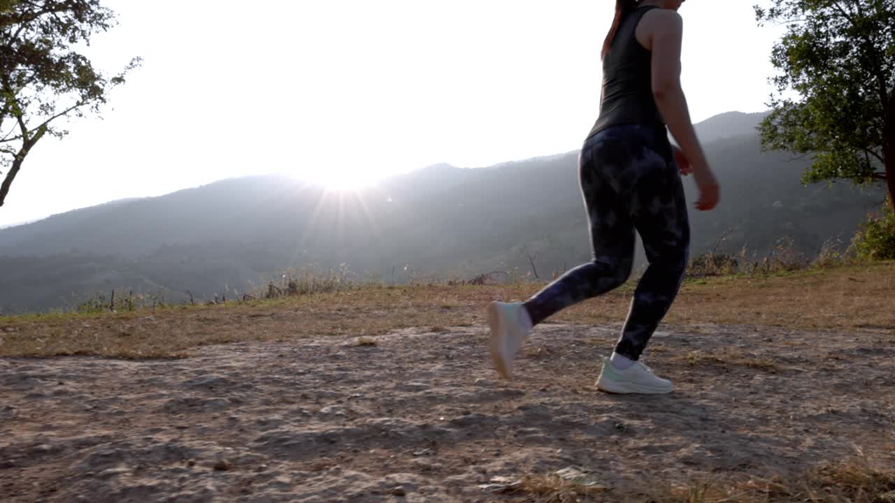 日落时分，穿着运动服的女子在山上慢跑。穿着运动胸罩在户外跑步的年轻亚洲女性。晚上锻炼身体。健康积极的生活方式理念。视频下载