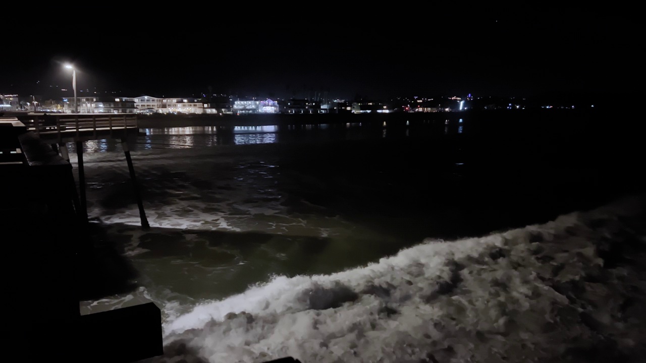 在夜晚的暴风雨中，巨大的海浪冲击着海滩上的海堤。广角镜头视频素材