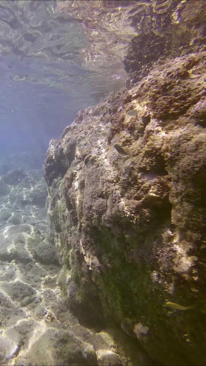 在阳光明媚的日子里，相机沿着海底上方的岩石向前移动，在沿海地区有大块的石头视频素材