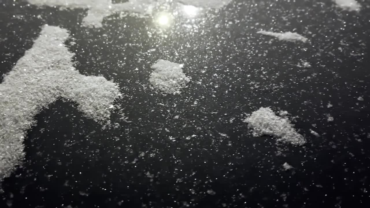 闪亮的雪在黑暗的背景上闪闪发光。视频下载