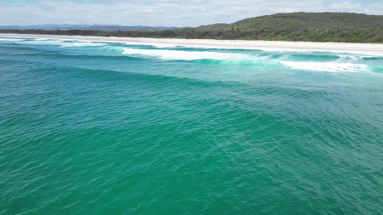 Aerial footage above the seaside of Australian Beach in Hastings Point with blue cloudy sky视频素材