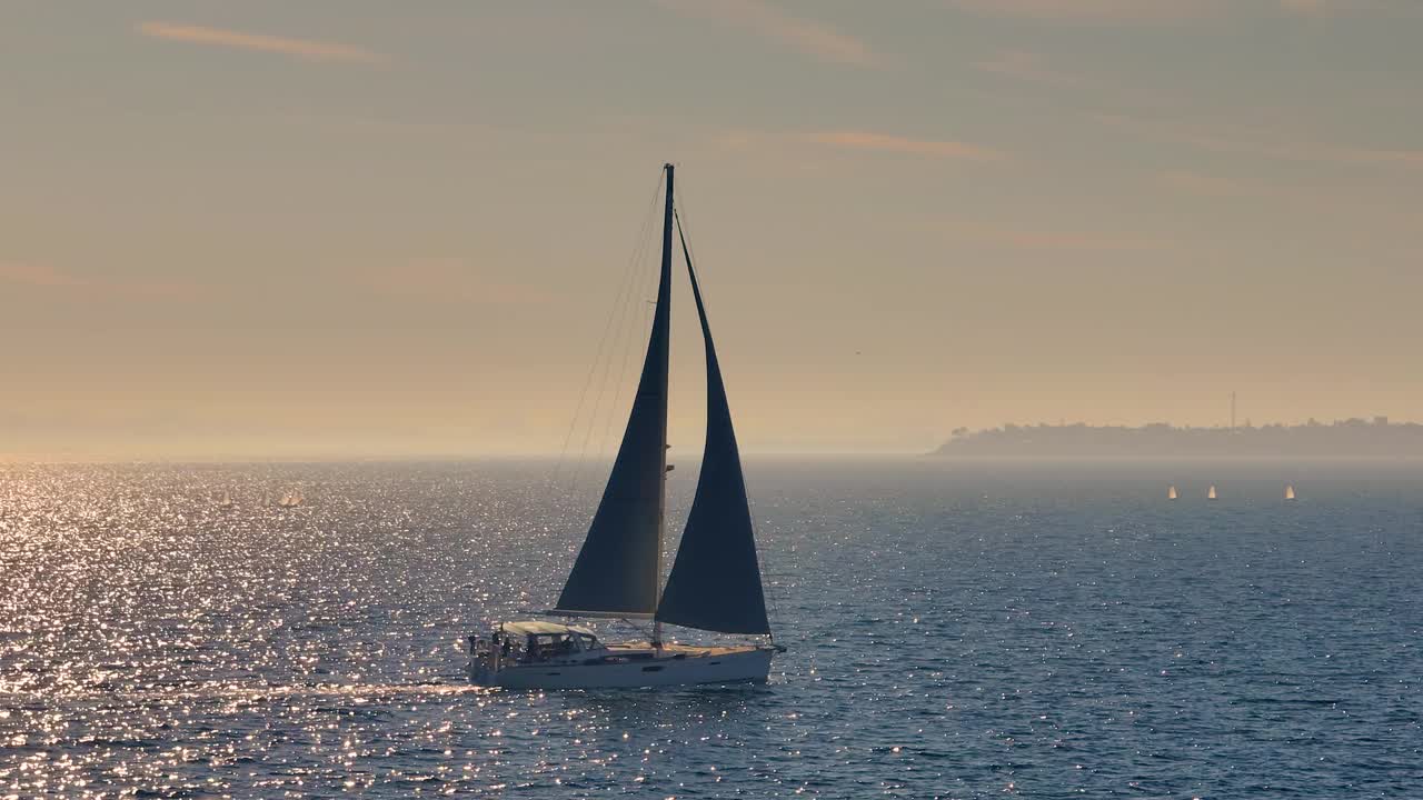 美丽的帆船航行在热带异国情调的海湾与深蓝色的大海。在夕阳的余晖中建立游艇的航拍。无人机拍摄的海上帆船的剪影视频素材