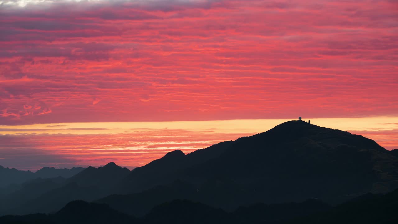 令人惊叹的日落将天空染成粉红色和橙色，勾勒出宁静的山脉。视频素材